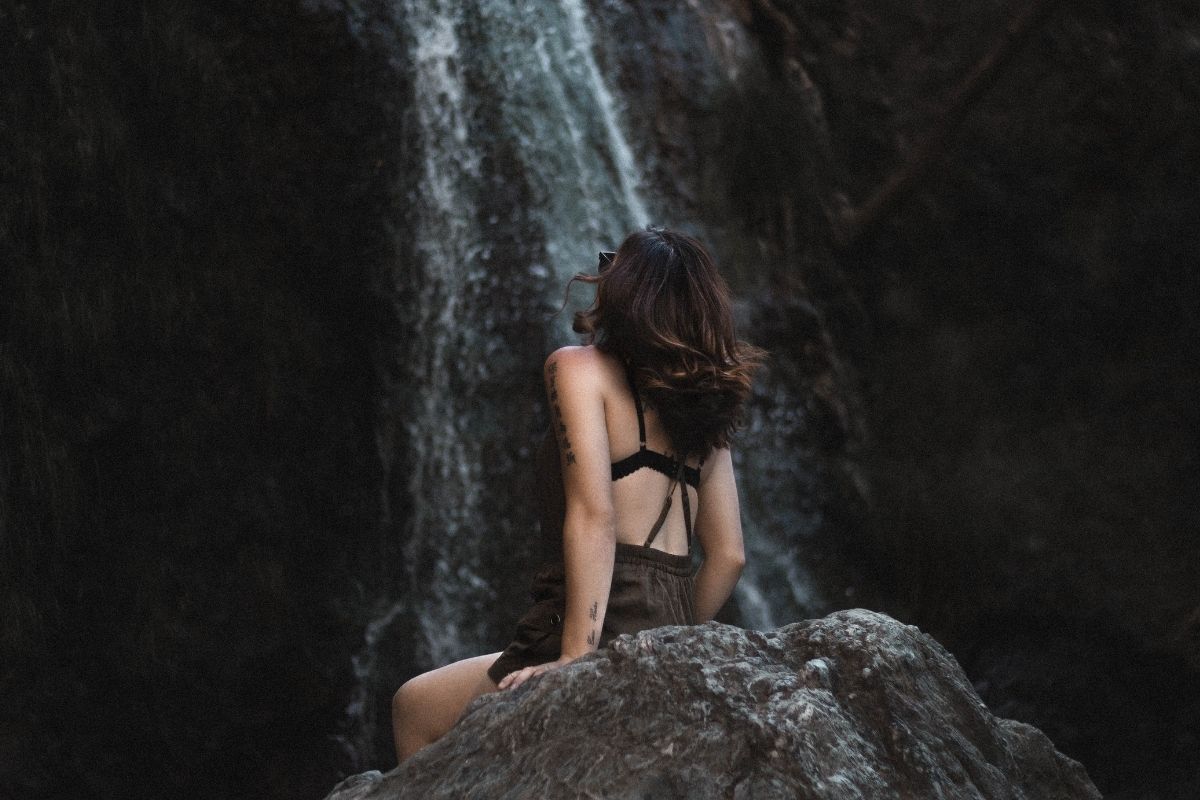 mulher observando a queda d'água em uma cachoeira